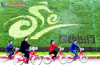 市民騎公共自行車路過市人民廣場一處花壇。記者 張馳
